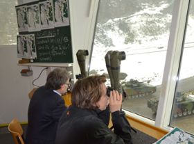 Regierungsrat Kaspar Schläpfer und Regierungsrätin Cornelia Komposch beobachten durch ein Fernglas einen Panzerangriff.
