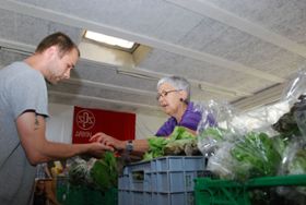Eine Helferin übergibt einem Bezugsberechtigten in der «tavola» Arbon verschiedene Gemüse aus dem aktuellen Angebot.