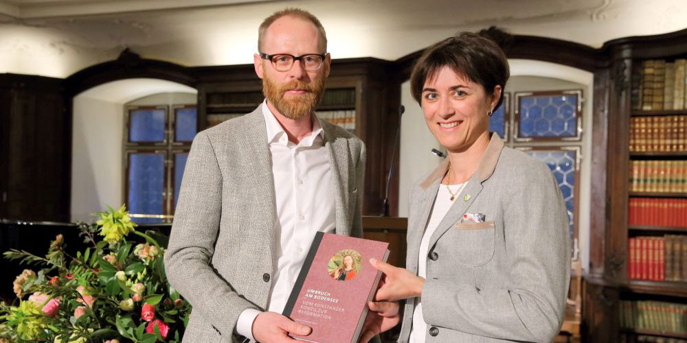 Urs Hofmann, Verlagsleiter NZZ libro, übergibt Regierungsrätin Monika Knill ein druckfrisches Exemplar des Buchs «Umbruch am Bodensee – vom Konstanzer Konzil zur Reformation».