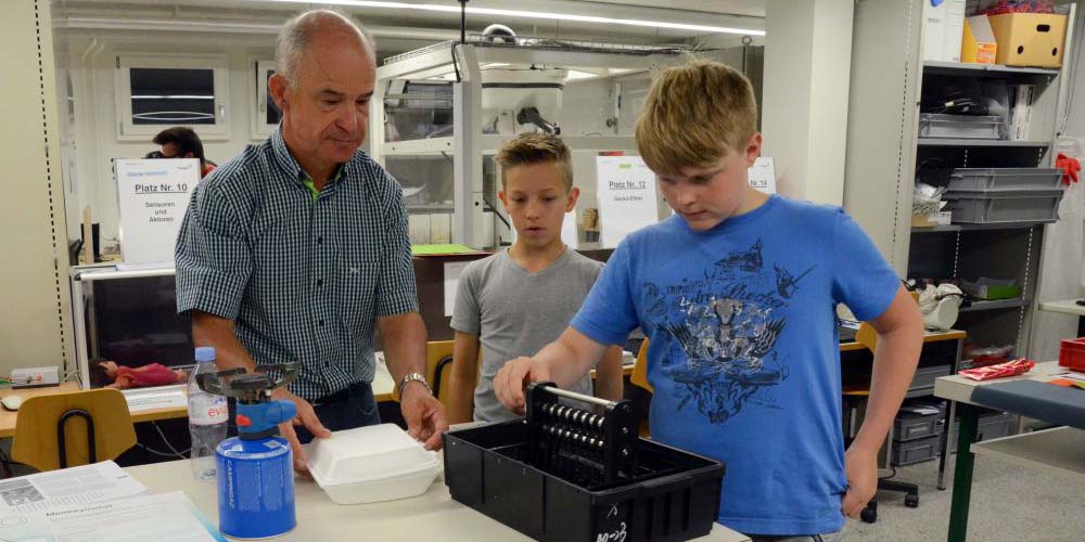 Kursleiter Niklaus Vogel hilft den Schülern bei einem Experiment.